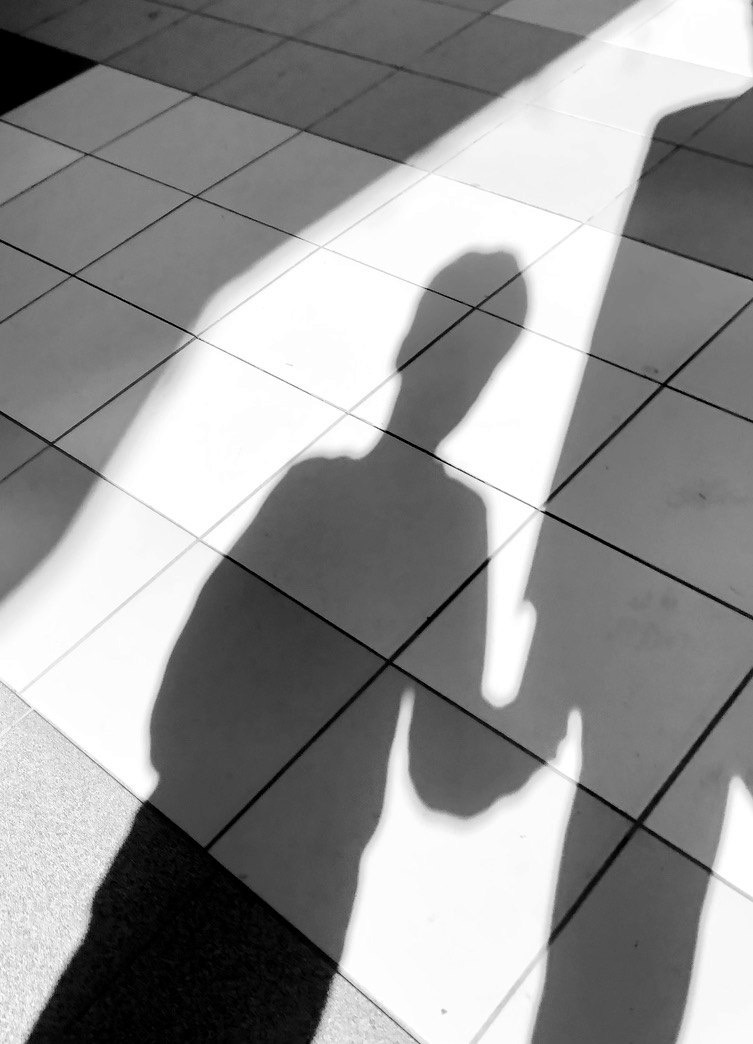 As sombras de um adulto e de uma criança de mão dada, no chão